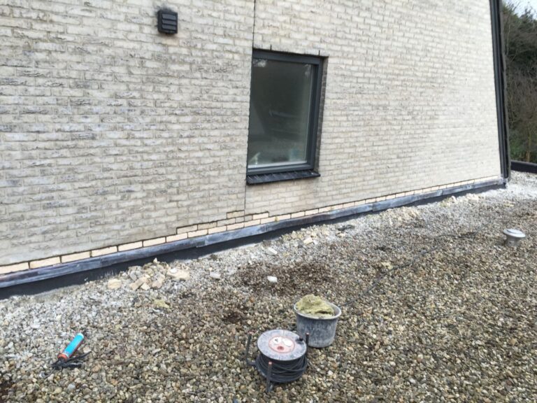 Lichte bakstenen gevel met loodslab en kiezelrand op plat dak — vakkundig gevel- en loodwerk door Dama Schoorsteenen & Geveltechniek